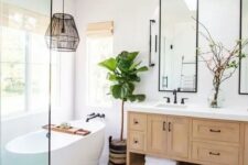 an airy modern farmhouse bathroom with a double timber vanity, framed mirrors, an oval tub, a boho rug, a black pendant lamp and a boho rug