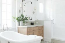 an airy modern farmhouse bathroom with a shower space, an oval tub, a basket, with a timber vanity and shades plus greenery