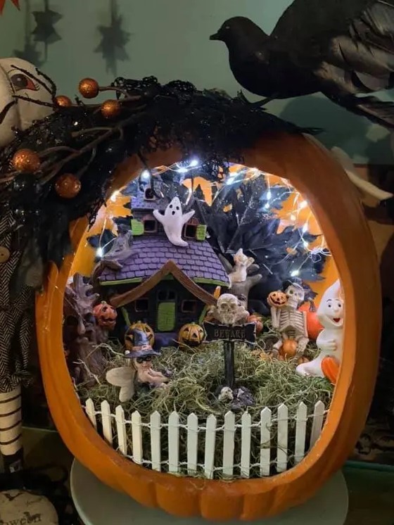 an orange pumpkin with lights, ghosts, jack-o-lanterns, hay and a fence plus a purple and green little house for Halloween
