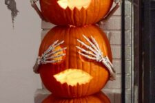 carved and stacked pumpkins with pumpkin eyes and skeleton hands will be nice Halloween decor for both indoors and outdoors
