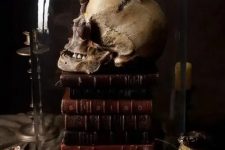 vintage Halloween decor of a stack of vintage books, a skull covered with snails, a cloche is a stunning moody solution