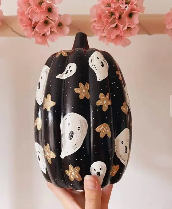 a beautiful painted black Halloween pumpkin with flowers and ghosts is a cool and chic solution