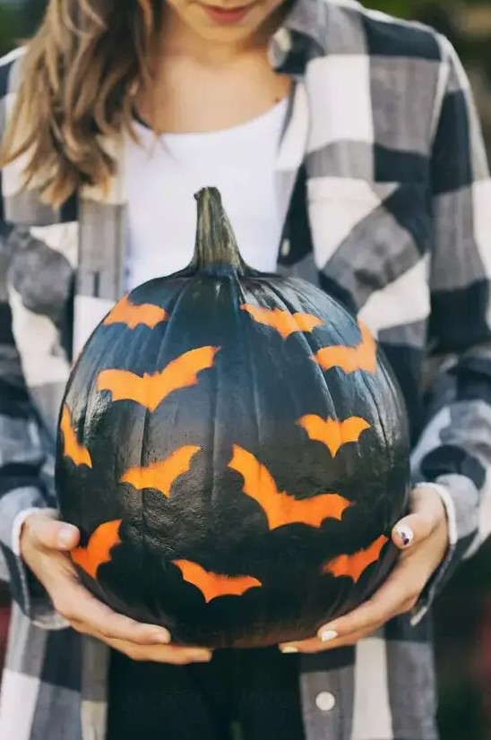 a black pumpkin stenciled with bats is a great idea for a modern rustic party or for your porch and it's easy to make