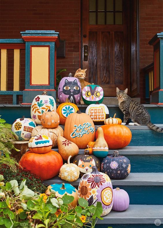 an arrangement of painted pumpkins with bold boho flowers, cats, owls, ghosts and letters is a fun idea for fall or Halloween decor