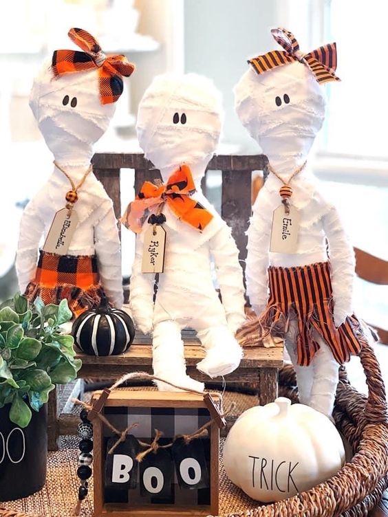 Halloween mummy dolls with tags and bows and some clothes, with pumpkins around are great for Halloween decor