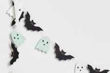 a Halloween garland of black bats and mint green and white ghosts is a cool and easy decor idea for your space