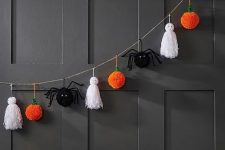 a Halloween garland of white tassels as ghosts, black spiders and orange pumpkin pompoms is a cool idea for styling a kids’ party