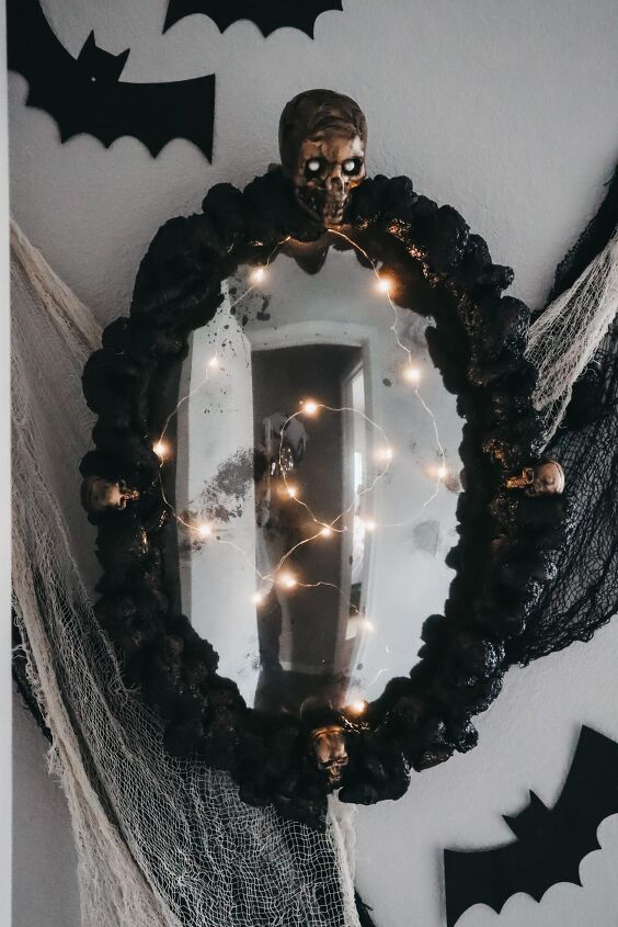 a Halloween mirror covered with black fabric and copper skulls plus lights is a creative and chic idea for styling a space