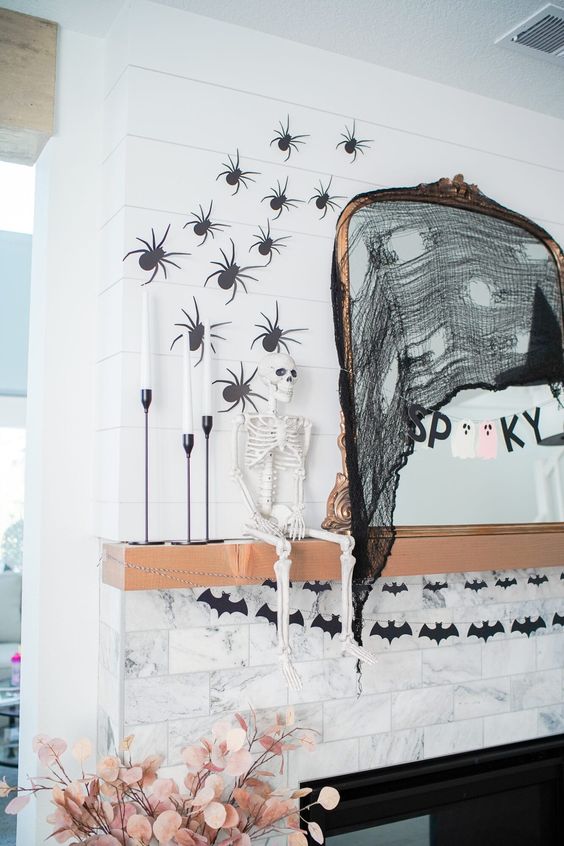 a Halloween mirror with black cheesecloth, a banner and a witch hat is a cool idea to style a space for Halloween