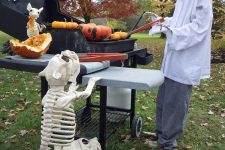 a Halloween skeleton scene with a skeleton cook cooking the pumpkins on the grill and skeleton dogs
