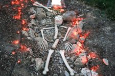 a Halloween yard with a skeleton placed in the grave, with lights and a tombstone is a cool idea