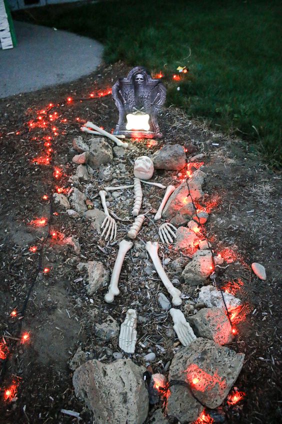 a Halloween yard with a skeleton placed in the grave, with lights and a tombstone is a cool idea