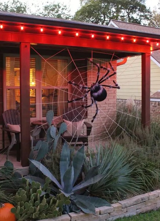 a back porch decorated with a giant spiderweb and a fluffy spider is a cool idea to style your outdoor space for Halloween without much effort