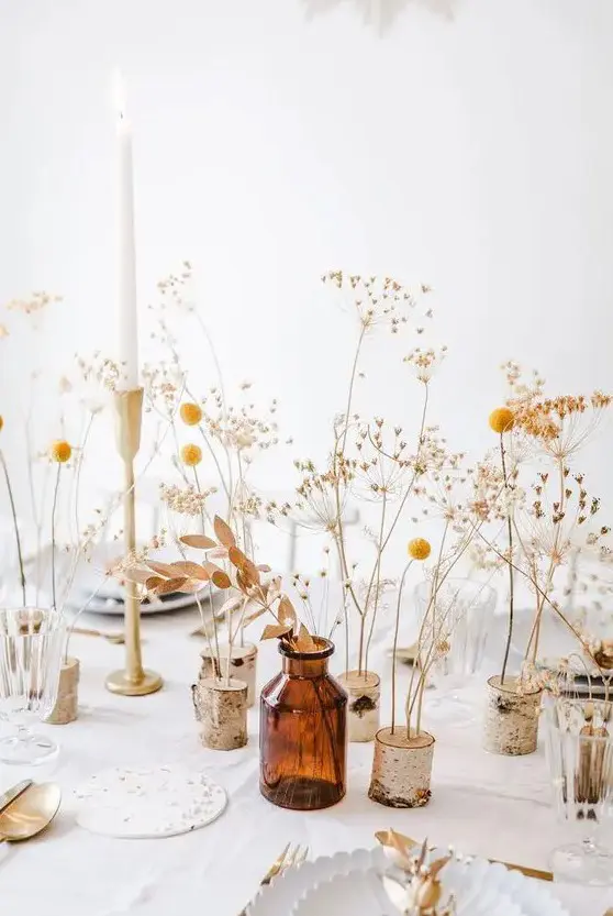 a beautiful and easy cluster centerpiece of billy balls, dried leaves, grasses and candles in tall candlesticks is a pretty rustic idea