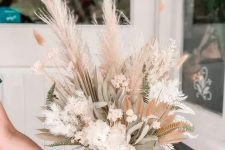 a beautiful dried flower centerpiece of white and pink dried blooms, grasses, leaves and fronds, fern leaves is amazing