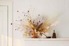 a beautiful fall flower arrangement with lots of leaves and some grasses, with a lot of dimension and texture that make it wow