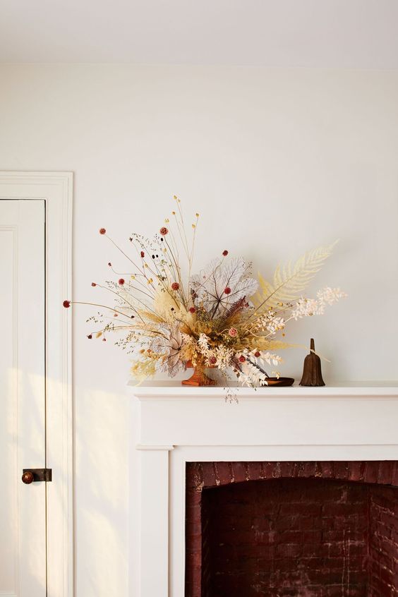 a beautiful fall flower arrangement with lots of leaves and some grasses, with a lot of dimension and texture that make it wow