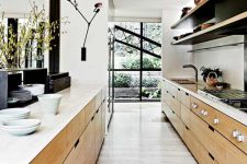 a beautiful modern narrow kitchen with stained cabinets, open shelves, white countertops, sconces and various decor