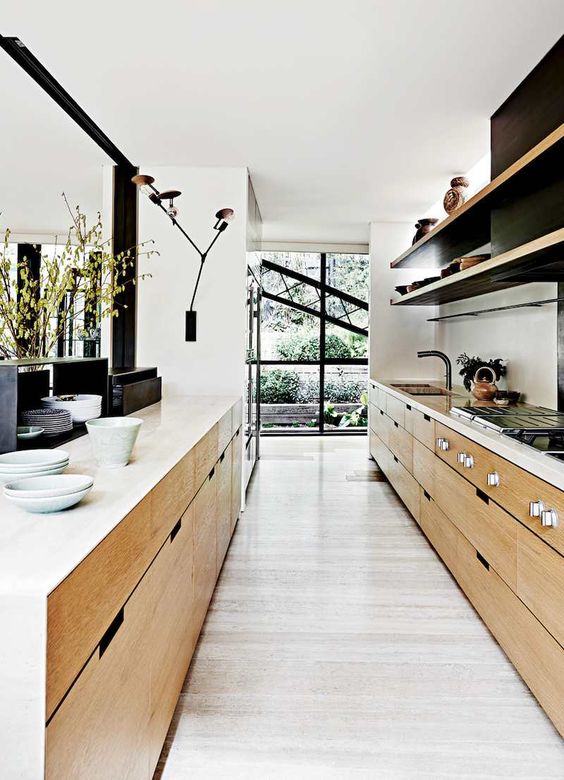 a beautiful modern narrow kitchen with stained cabinets, open shelves, white countertops, sconces and various decor