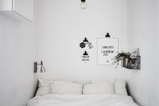 a black and white narrow Scandinavian bedroom with a bed squeezed in, a shelf, some decor and black and white bedding
