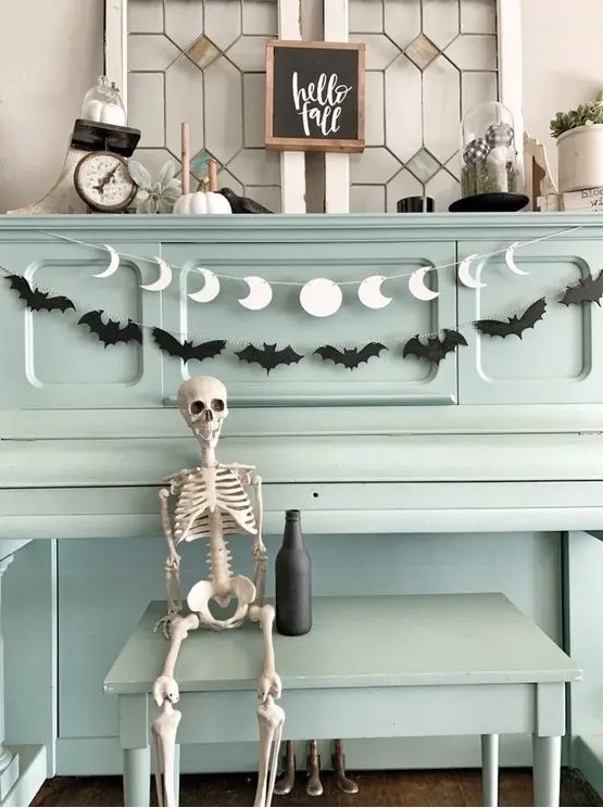 a black bat garland paired with a white moon phase one are a cool and simple combo for Halloween decor