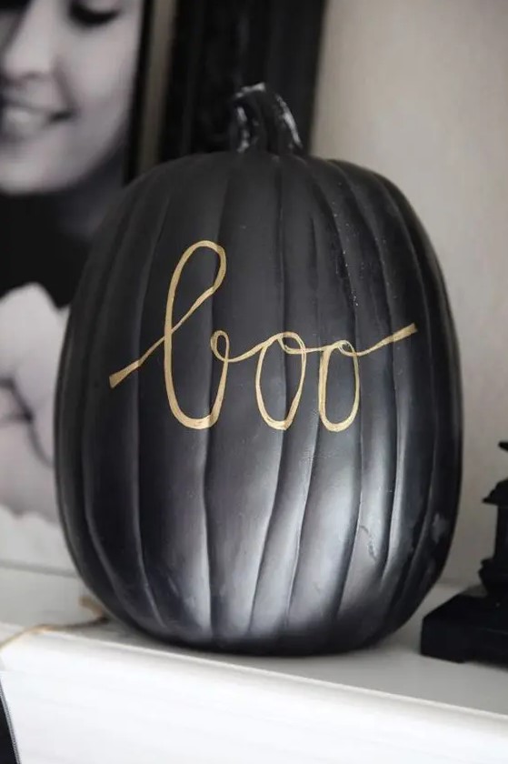a black pumpkin decorated with a gold sharpie is a simple and stylish solution for modern Halloween decor
