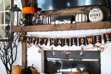a bold and chic Halloween mantel with black and white pumpkins, a bright bunting and orange and black pumpkins