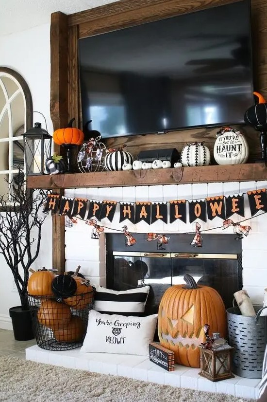 a bold and chic Halloween mantel with black and white pumpkins, a bright bunting and orange and black pumpkins
