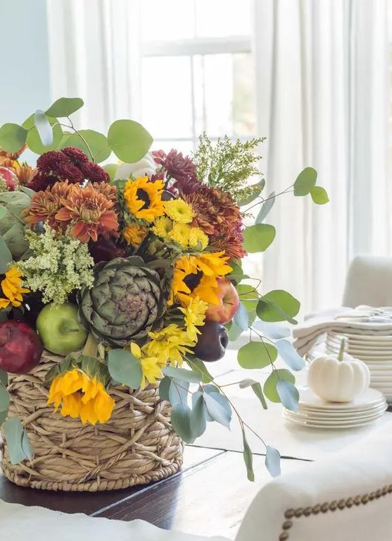a bold fall centerpiece of yellow, orange and rust and burgundy blooms, greenery, faux apples and pears plus foliage