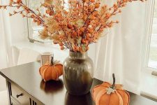 a bright dried flower arrangenment with berries and grasses done in orange and neutrals is a cool idea for the fall