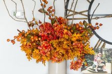 a bright faux flower arrangement in mustard, red and rust, with berries and twigs, is a great idea for the fall