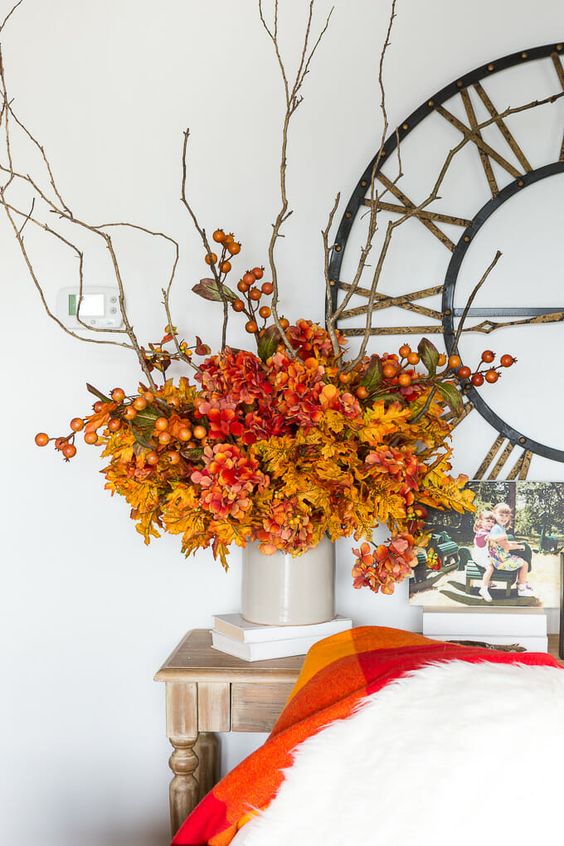 a bright faux flower arrangement in mustard, red and rust, with berries and twigs, is a great idea for the fall