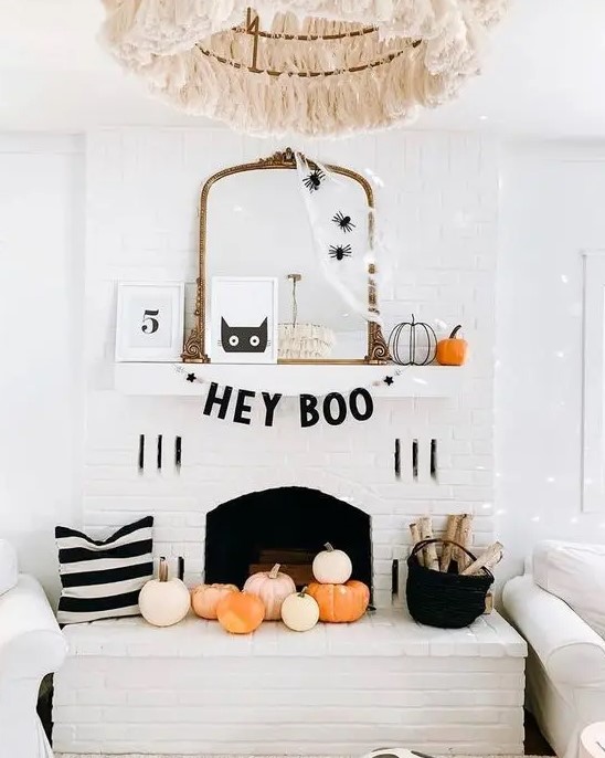 a chic Halloween mantel with spiderweb and spiders on the mirror, pumpkins, a black garland and pumpkins in the fireplace