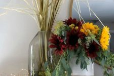 a chic fall faux flower arrnagement with lots of eucalyptus, burgundy and yellow blooms plus a grass arrangement