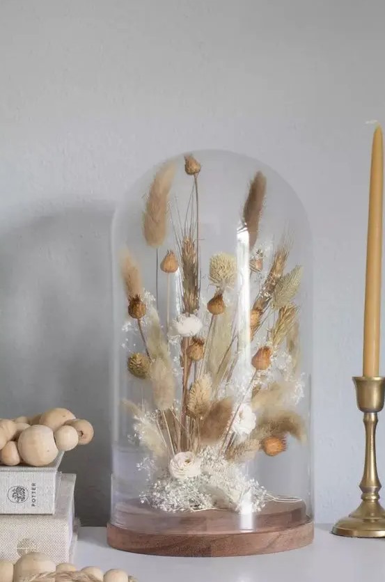 a cloche with a simple dried grass arrangement and seed pods is a cool boho or rustic decor idea that will soften any home decor