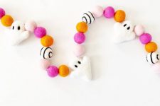 a colorful Halloween garland of felt balls and white felt ghosts is a lovely idea to style your space for Halloween in a colorful way