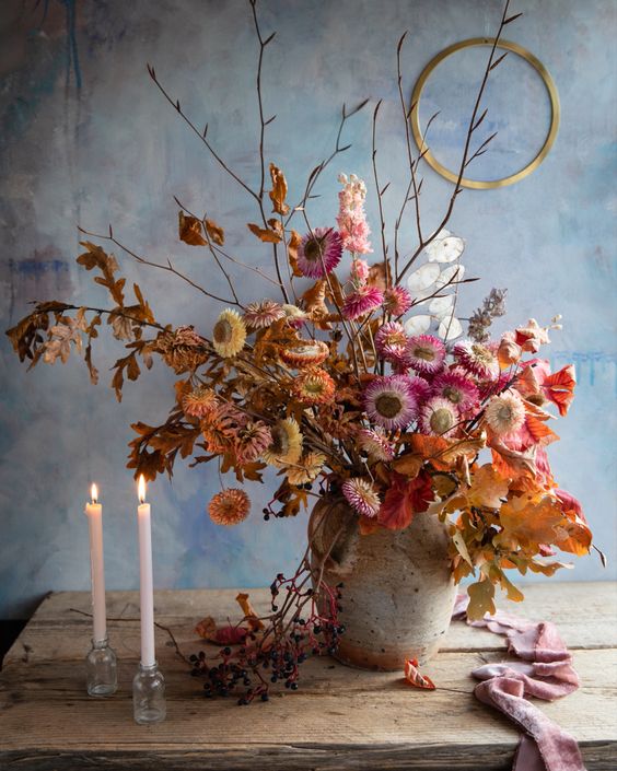 a colorful dried flower arrangement with orange, pink and yellow dried flowers, dried leaves and twigs plus lunaria