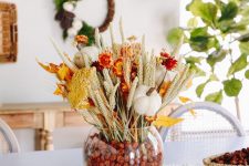 a colorful fall dried flower arrangement with blooms, grasses and little pumpkins plus some dried berries in the vase