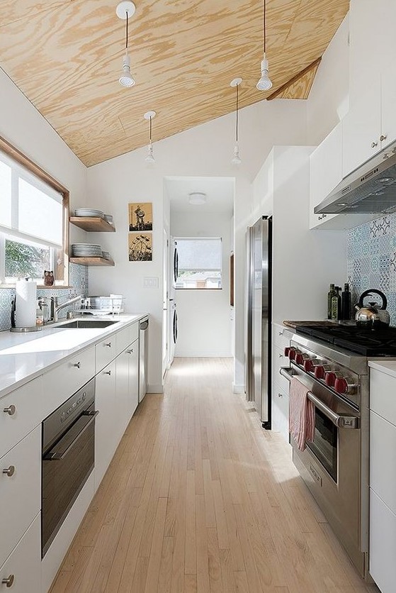 a contemporary white galley kitchen with a plywood ceiling with pendant lamps a wooden floor and a blue tile backsplash