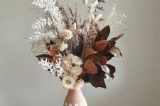 a cool centerpiece of dried blooms, leaves, grasses placed into a printed pink vase is a cool idea for a fall space