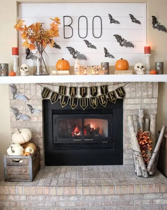 a fabulous Halloween mantel with grey bats, pumpkins, bright candles, branches with leaves is wow