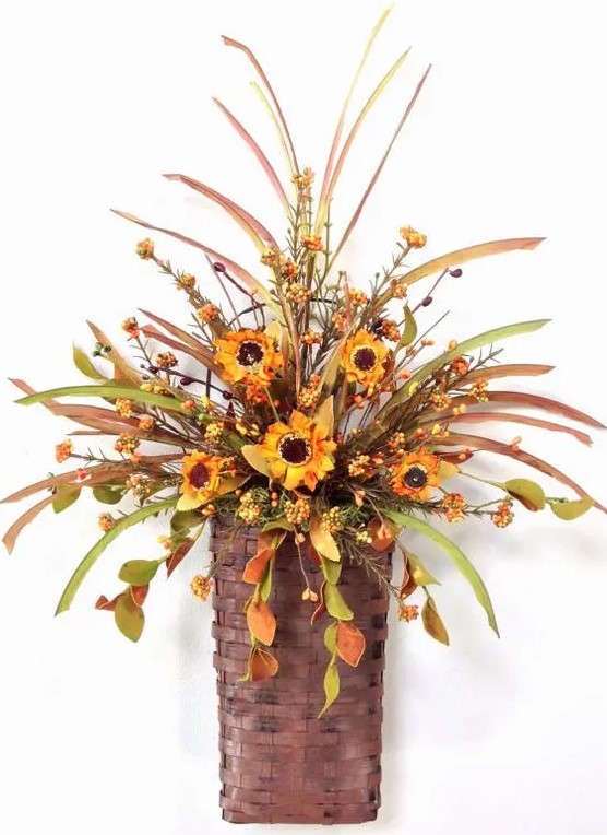 a fall arrangement of foliage, berries and bright orange faux blooms in a basket is a stylish decoration