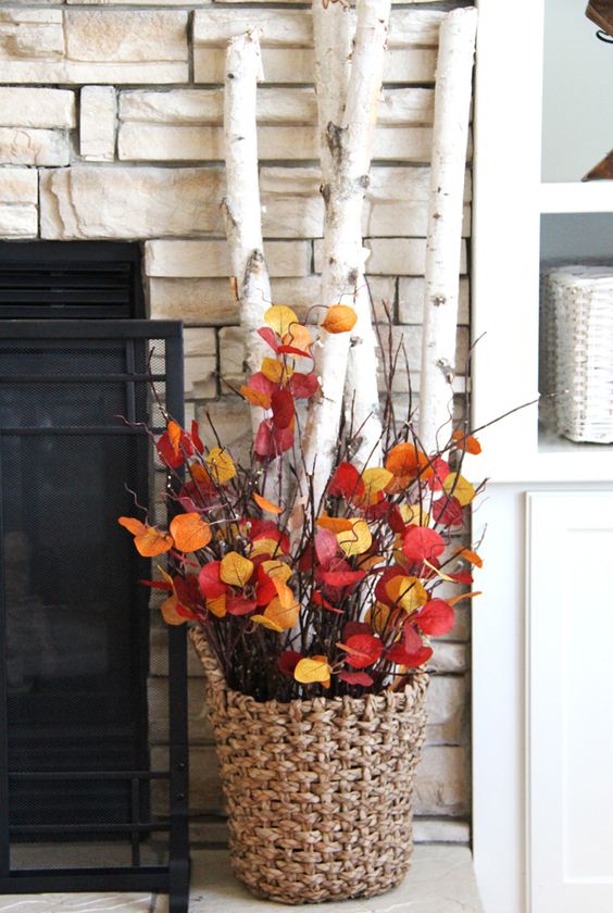 a fall arrangement of twigs and bold fall leaves in a basket is a cool idea for fall decr, both indoors and outdoors