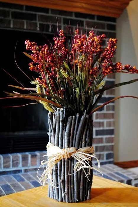 a fall decoration of greenery and berry branches and with twigs and sticks covering the bouquet looks very natural