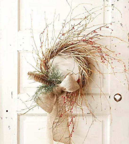 a fall twig wreath with greenery, feathers, berries and a burlap bow is a cool and easy boho decoration