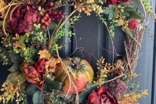 a fall wreath of leaves, faux bright blooms, pumpkins and twigs of various kinds is very chic