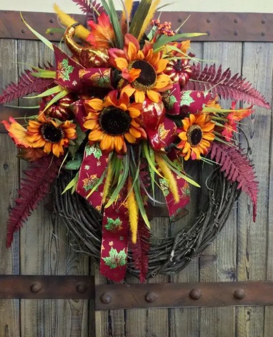 a fall wreath with bright faux blooms, leaves and ribbons is a stylish and long-lasting outdoor decoration with a rustic feel