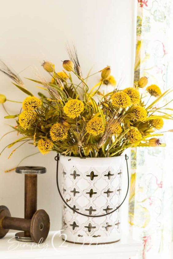 a faux flower arrangement in mustard and yellow, with seed pods, is a cool idea for fall home decor