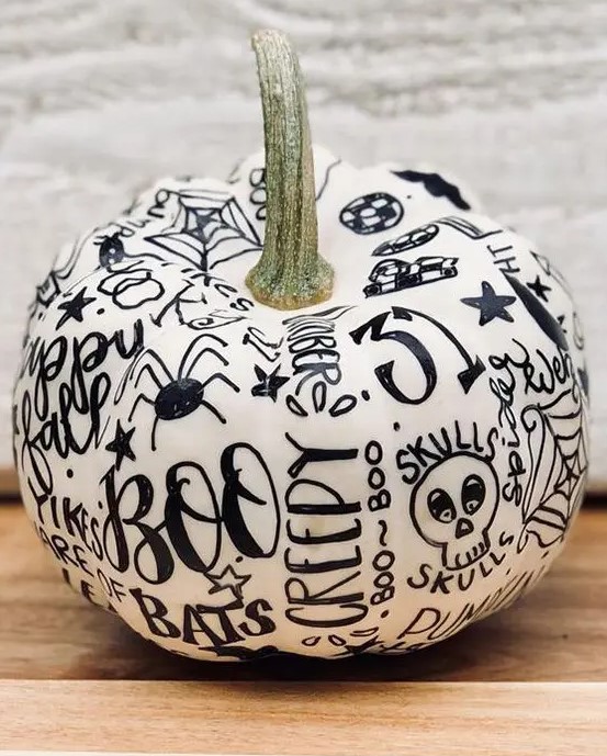 a fun contrasting pumpkin in white, decorated with a black sharpie, can be a nice idea for a modern Halloween party or just as decor