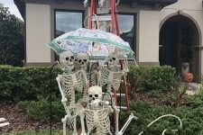 a fun skeleton scene sitting on a ladder and with an umbrella is a cool idea for Halloween outdoor styling